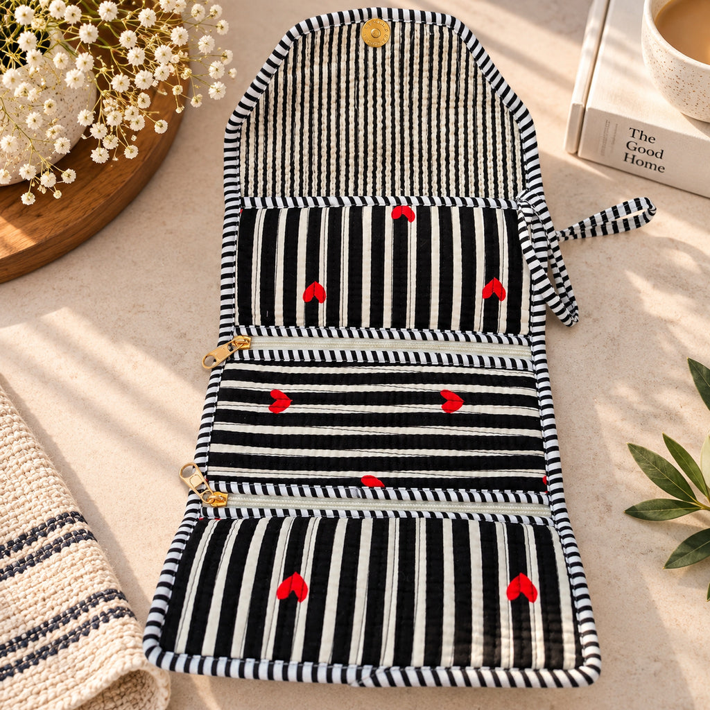 Folded black and white striped quilted organizer with embroidered red hearts and gold snap button