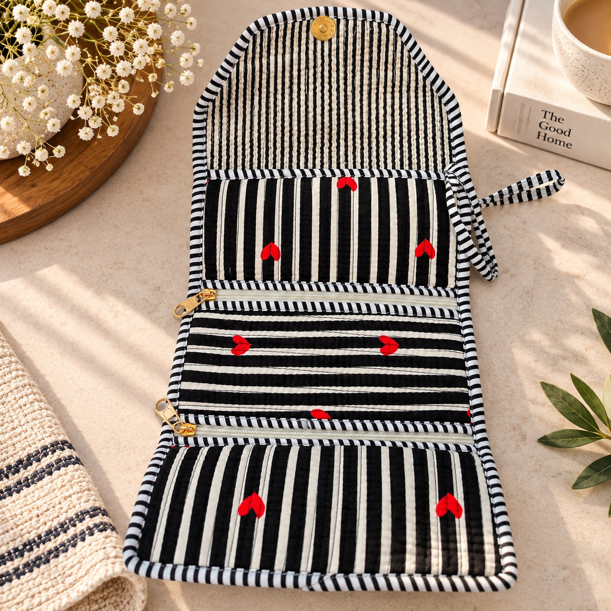 Folded black and white striped quilted organizer with embroidered red hearts and gold snap button